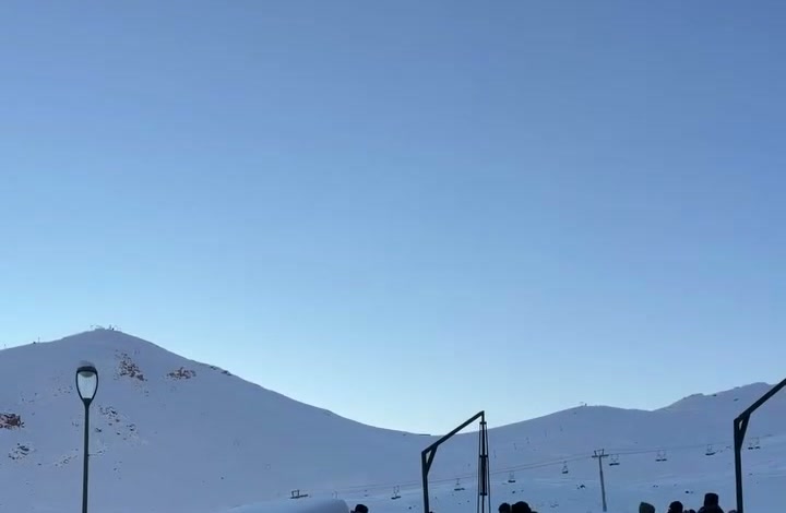 A base do Valle Nevado com gente circulando e, ao fundo, a montanha branca com o teleférico.